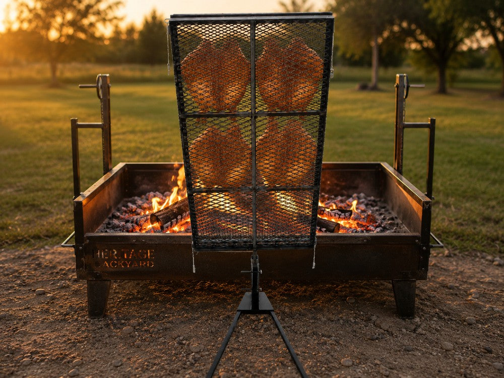 241264 Asado Poultry Cross with Adjustable Base used for cooking split chicken over a wood-fired steel fire pit in a live-fire outdoor cooking setup.