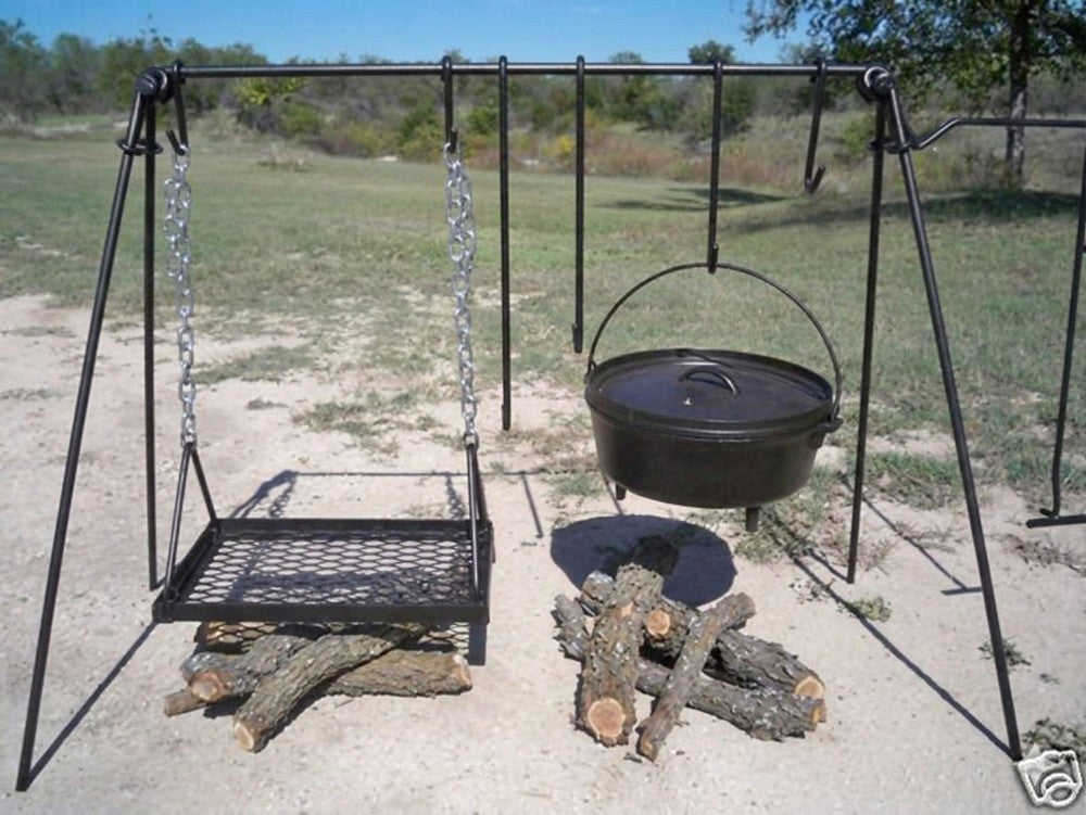 Campfire cooking setup with Dutch oven and grill grate suspended from a portable quadpod campfire stand.