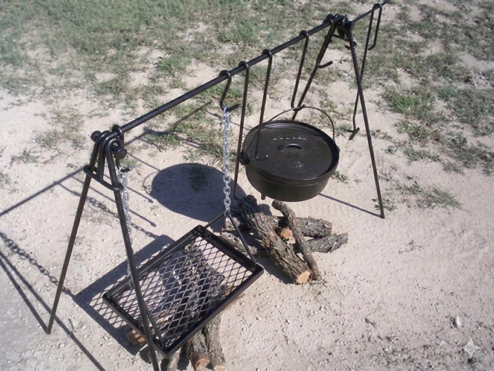 Side view of a portable quadpod campfire cooking stand with hanging grill grate and Dutch oven hook.