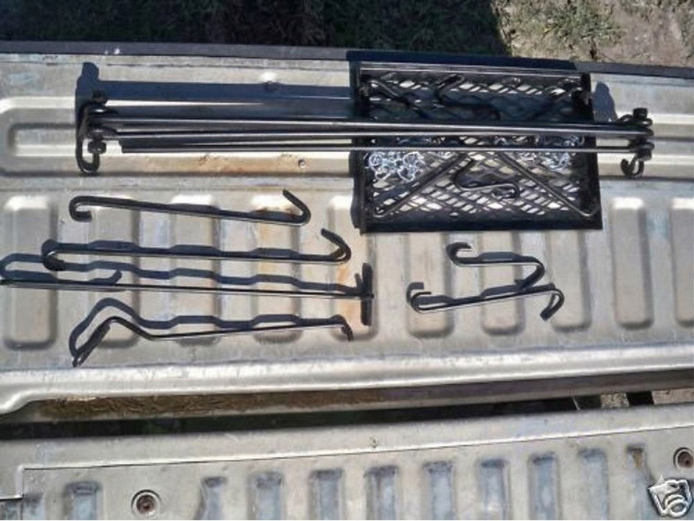 Portable quadpod campfire grill system components including grill grate, hooks, and frame laid flat for transport.