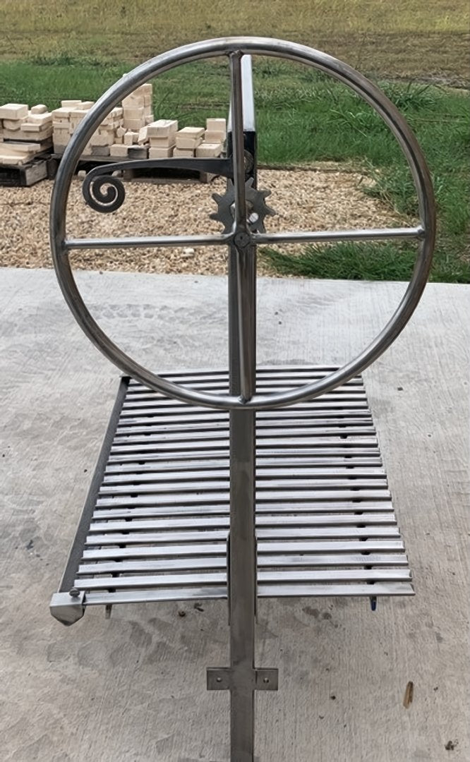 Close-up of the Argentine grill height adjustment wheel used to raise and lower the grill grate for precise live-fire cooking control
