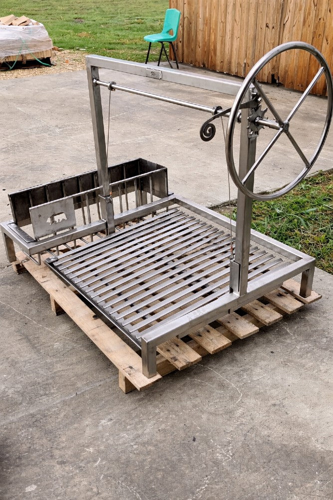 Stainless steel adjustable stilt grill with side brasero and V-grate, featuring side wheel height control for wood or charcoal cooking