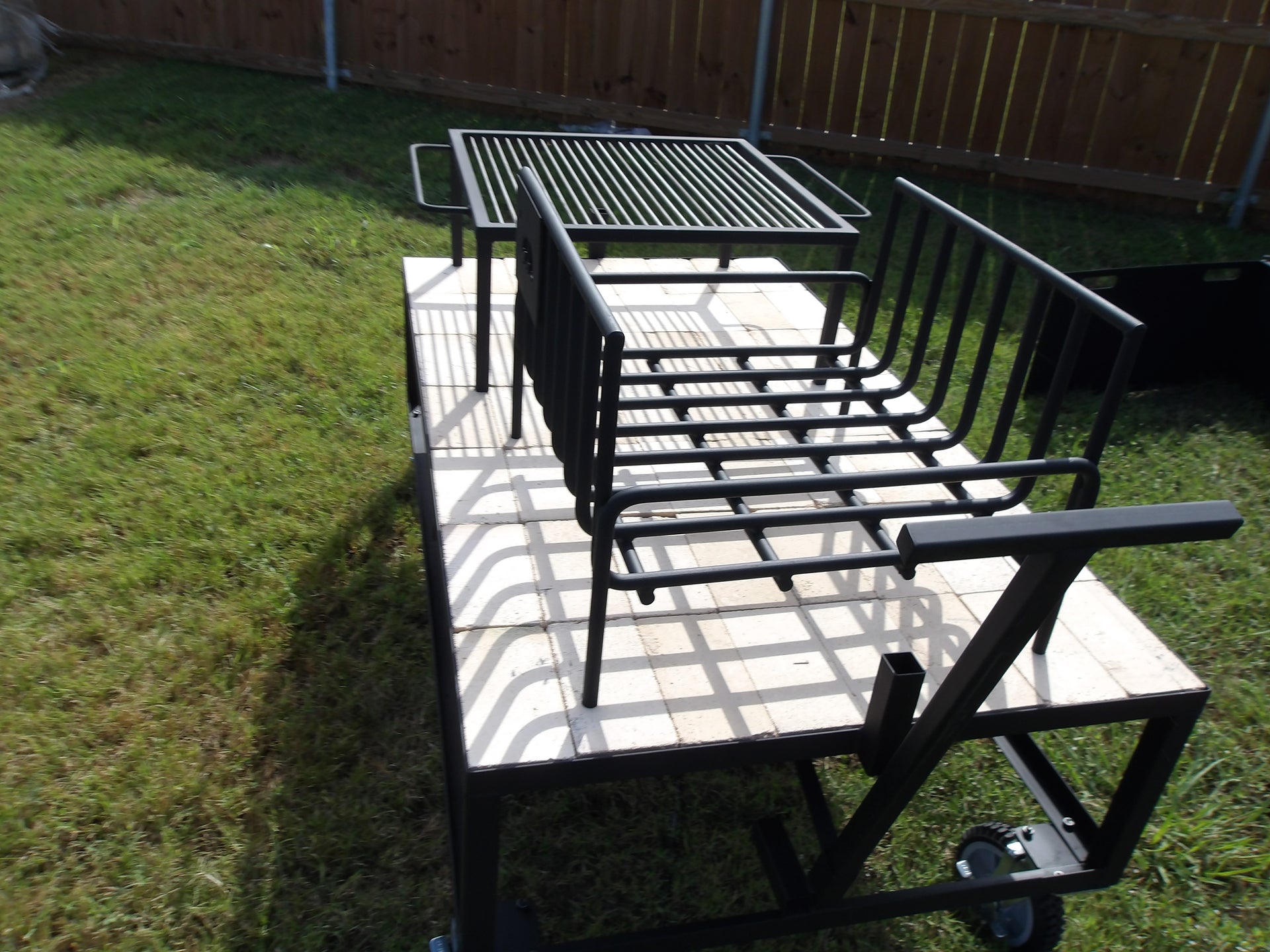 Exhibition Fire Table with All Terrain Casters, Small Asado Grill, Heavy Duty Large Brasero, and a Three-Sided Hinged Wind Block