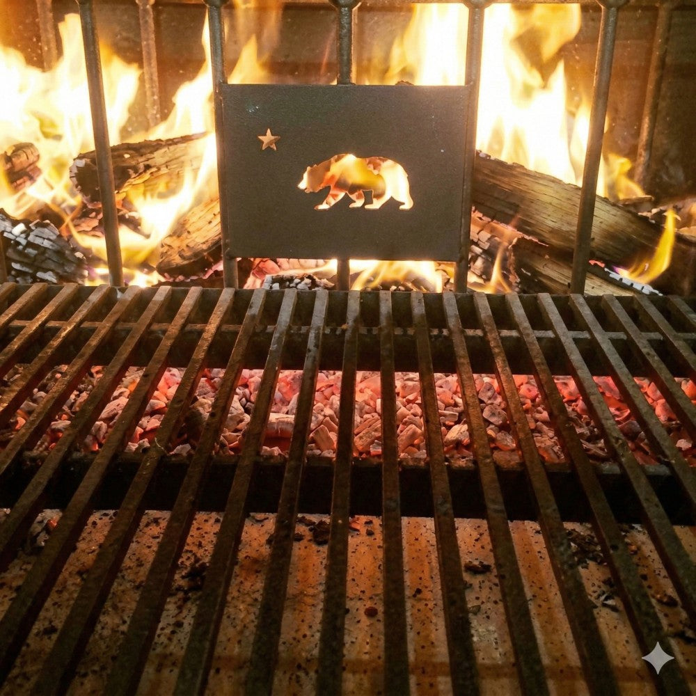 Argentine grill with rear brasero in active use, showing V-grate over glowing coals and wood burning behind the bear logo panel.