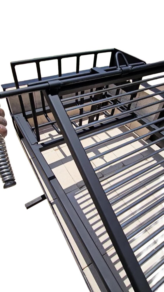 Close-up of Built-In Uruguayan Grill showing side brasero and adjustable grill frame made from heavy-duty black steel.