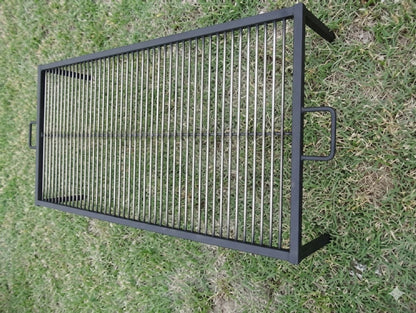 Large black steel Asado grill grate with vertical bars and side handles, designed for open-fire cooking over wood or charcoal.