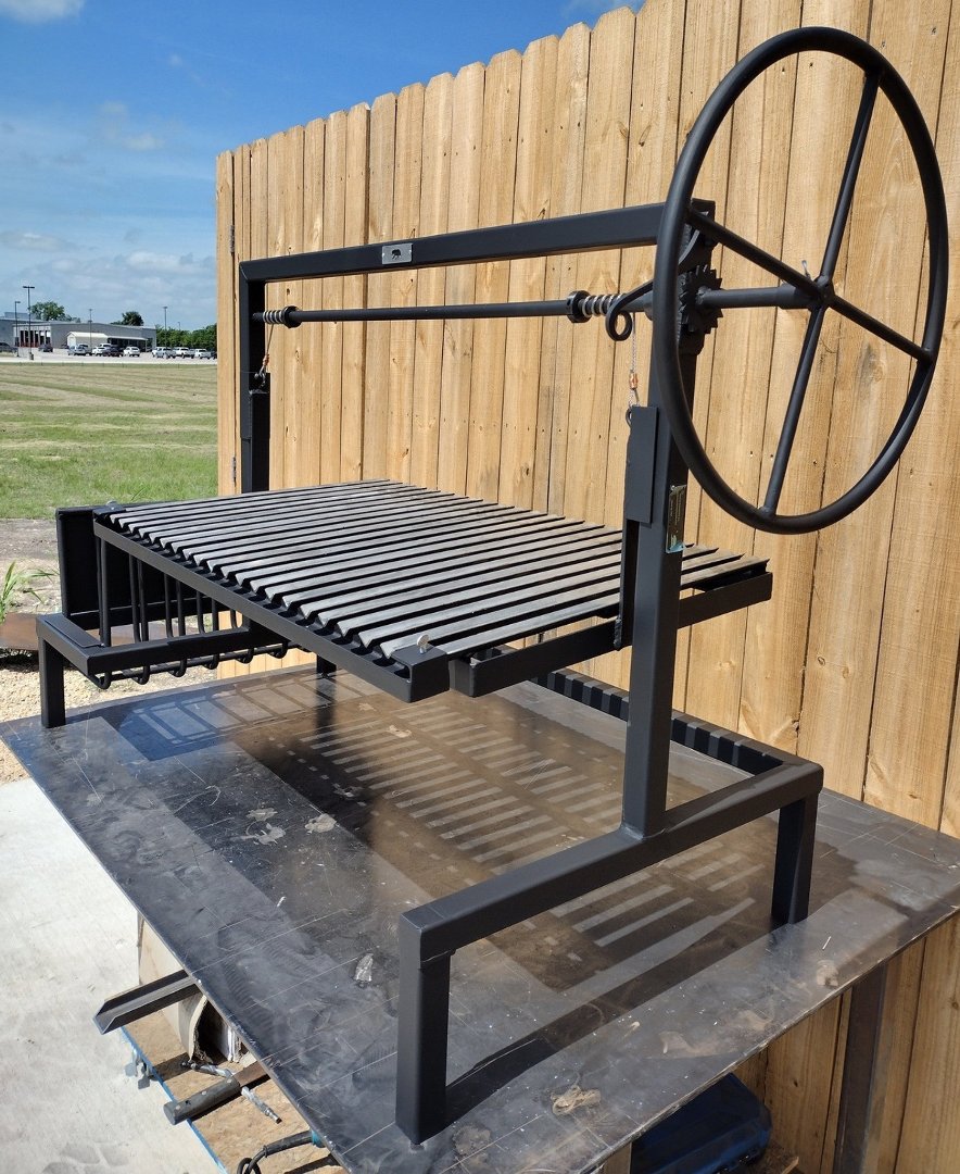 Top view of Heritage Backyard stilt grill kit showing large side wheel and adjustable Argentine grill grate